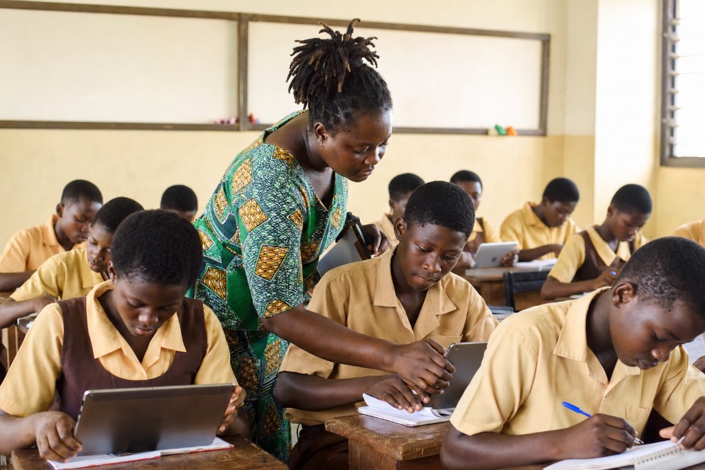 Teacher supporting students using tablets in a classroom